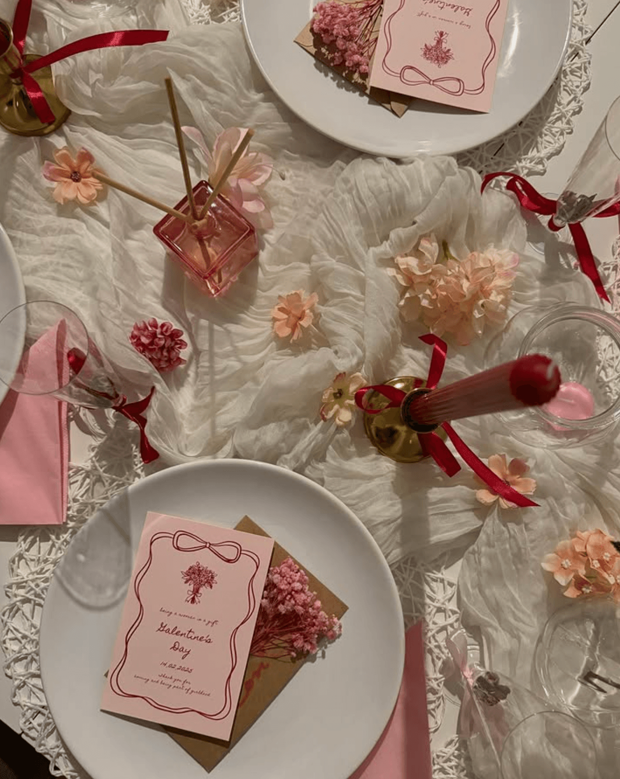 Hand-illustrated pink place cards with crimson ribbon borders, dried flowers and candles on a layered tablescape