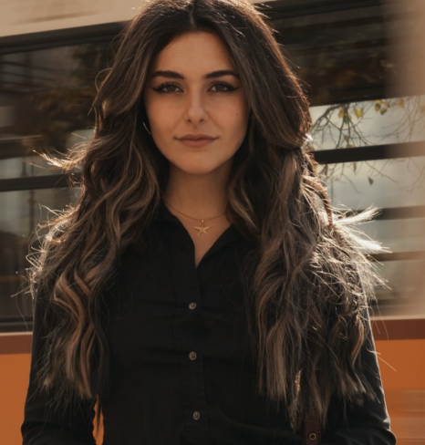 Portrait of Nur, founder of Light Within Events, outdoors in a black shirt with her long dark hair catching the afternoon light