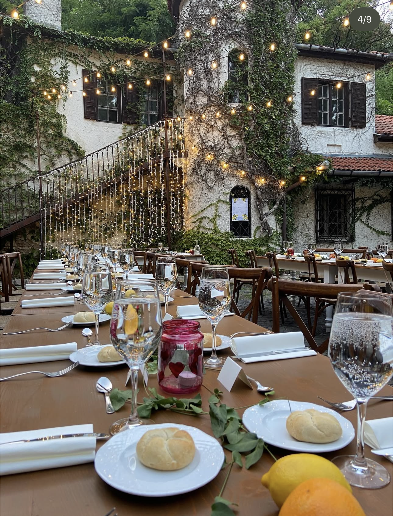 Ivy-covered courtyard venue strung with festoon lights, long tables set for a wedding dinner