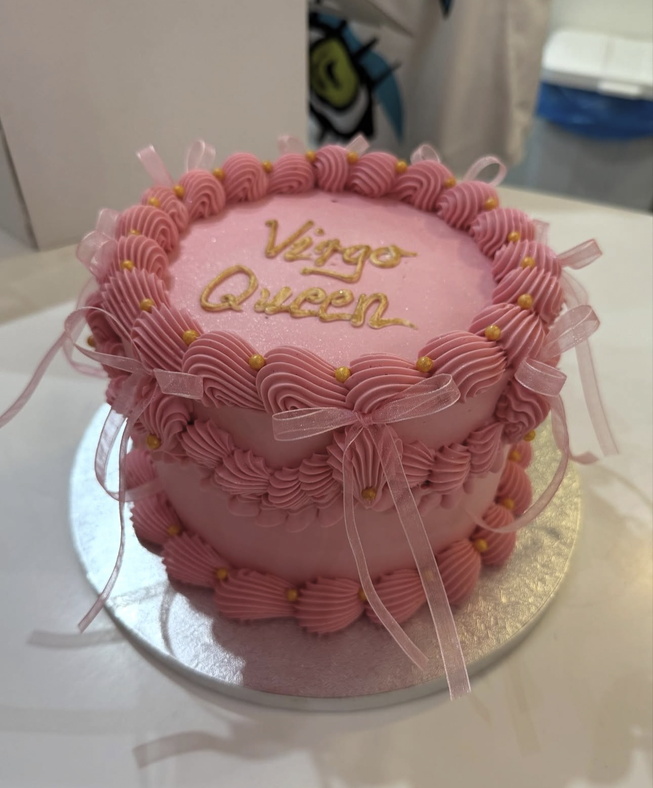 Vintage-style pink birthday cake piped with ruffles, ribbon bows and gold pearls