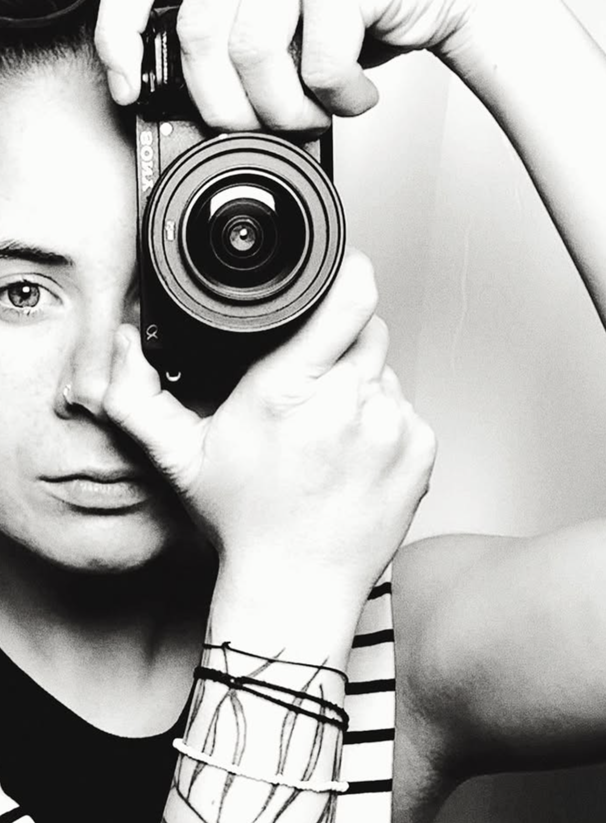Black and white self-portrait of photographer Nagy Niki, camera raised to one eye